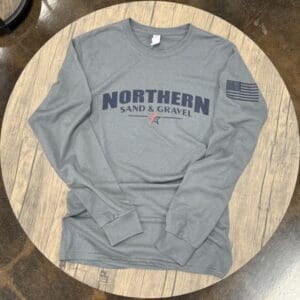 A gray long sleeve shirt sitting on top of a wooden table.