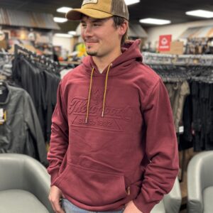 A man in a hat and jacket standing next to some chairs.
