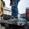 A man standing on the back of a truck.