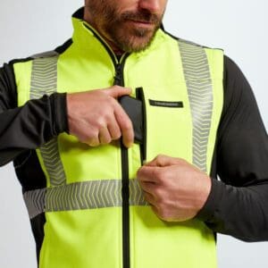 A man in yellow vest holding onto the side of his jacket.