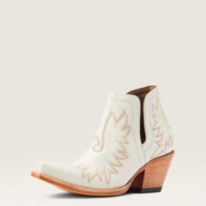 A white cowboy boot with brown stitching and an orange heel.