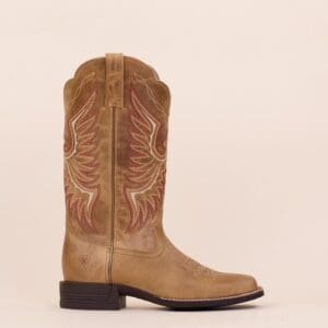 A pair of cowboy boots on display in front of a white wall.