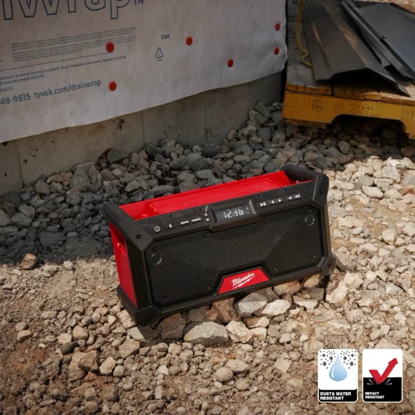 A red and black speaker sitting on top of gravel.